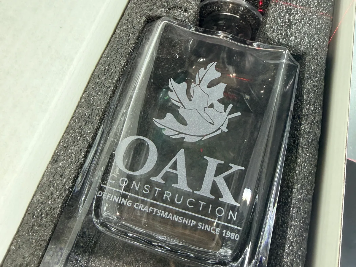 Glass whiskey decanter laser engraved with the OAK Construction company logo