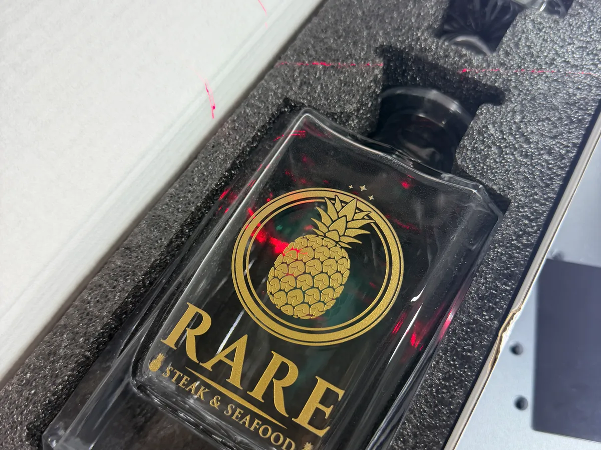 Glass decanter laser engraved with the RARE Steak and Seafood gold pineapple logo
