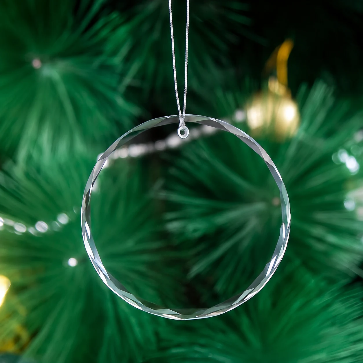 Clear round faceted glass ornament hanging on a Christmas tree